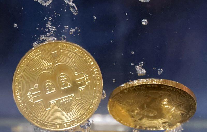 Illustration shows representations of cryptocurrency Bitcoin plunging into water